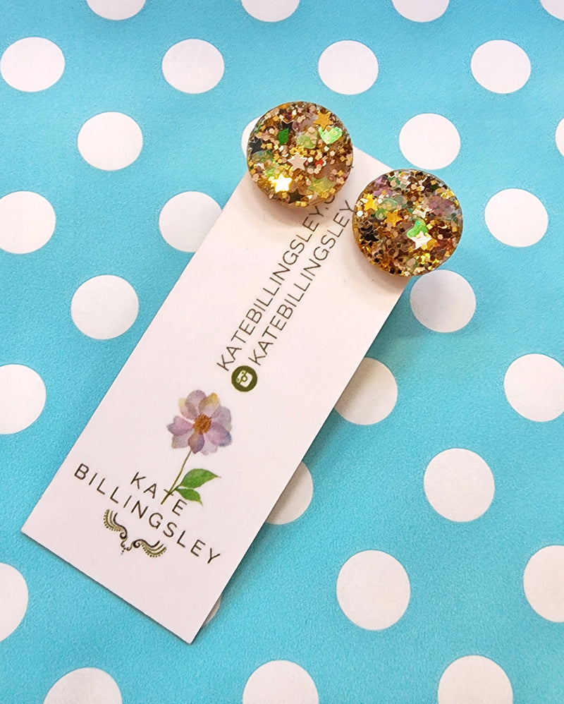 Glittery round earrings on a Kate Billingsley card against a polka dot background